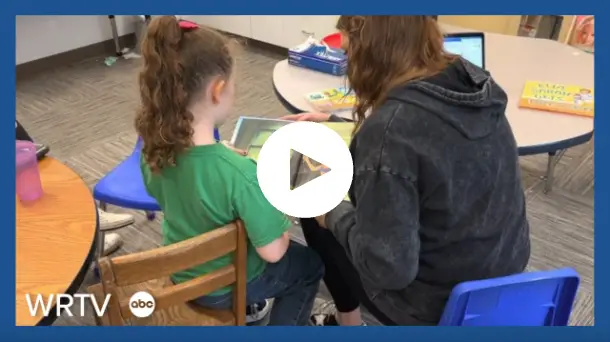 behavior technician and child reading at a table
