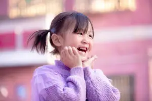 Smiling young girl with autism enjoying outdoor play, showing joy and progress from ABA therapy at home.