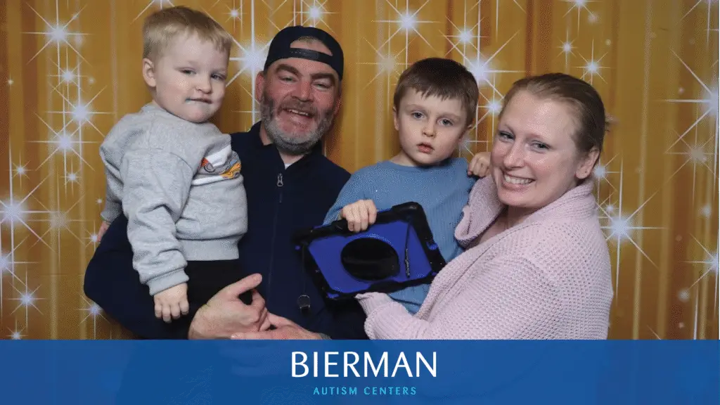 A family celebrates Sensory Santa with smiles, snuggles, and a tablet used for communication support.