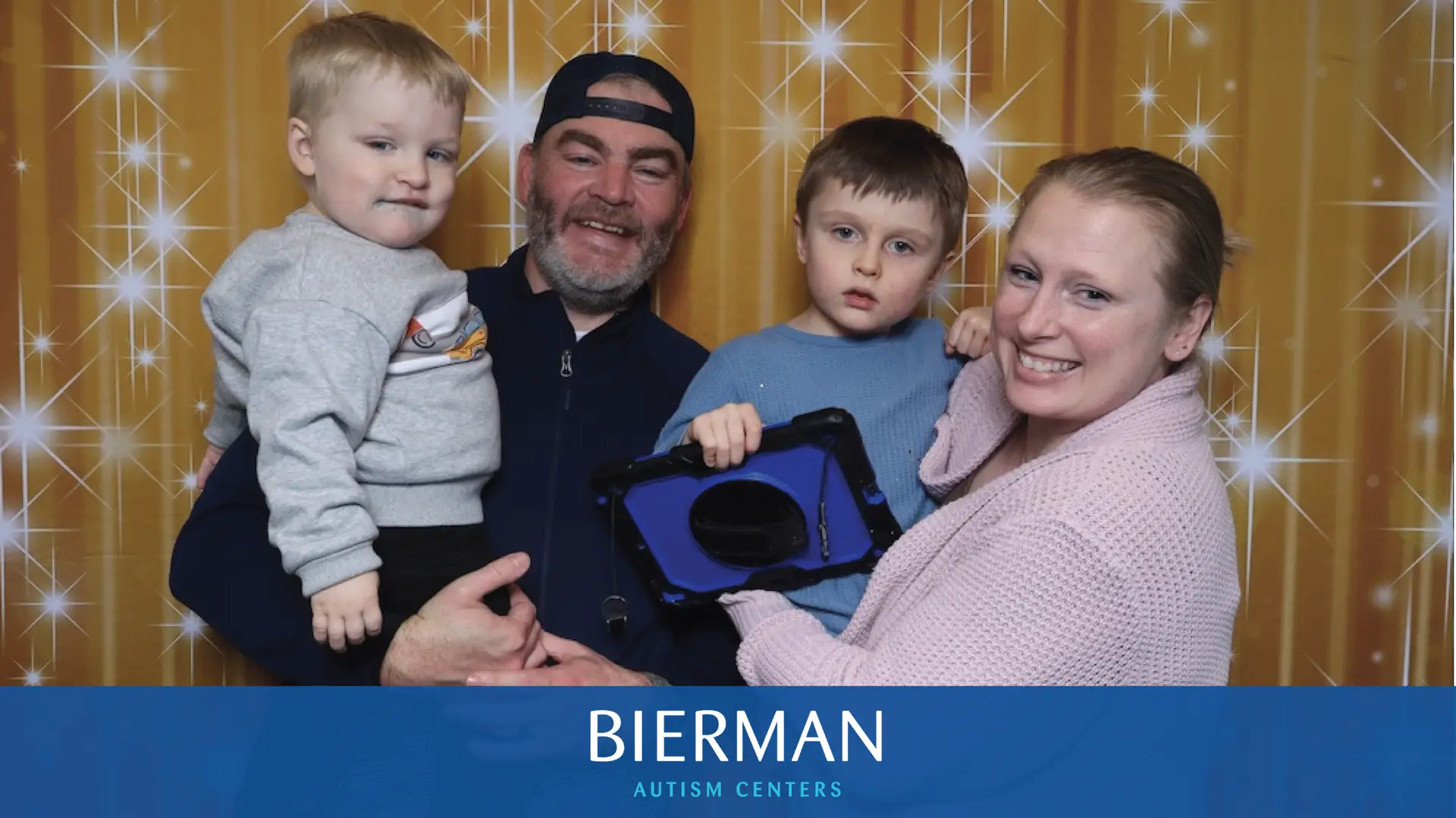 A family celebrates Sensory Santa with smiles, snuggles, and a tablet used for communication support.