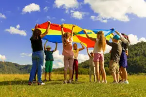 Children engaging in an outdoor parachute activity that supports social skills and cooperative play as part of ABA therapy at Bierman Autism Centers.