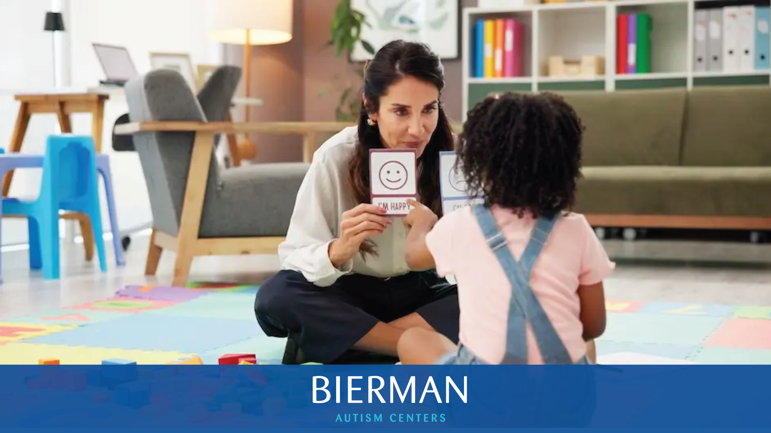Clinician using visual emotion cards during a play-based ABA therapy session with a young child at Bierman Autism Centers.